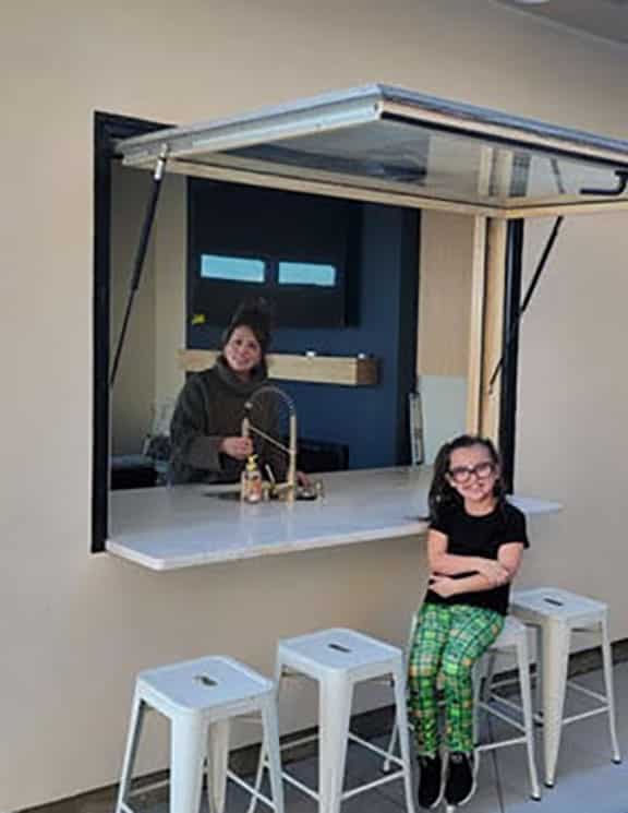 Opened gas strut kitchen window exterior with woman and little girl