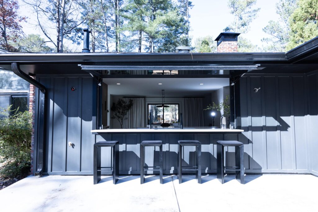 Exterior view of an opened motorized pass-through window, showing the countertop extending outwards and the seamless transition between indoor and outdoor space.