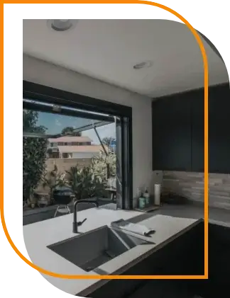 OpenUp® window made with insulated glass fully open above a kitchen countertop, linking the indoor kitchen space with an outdoor patio area.